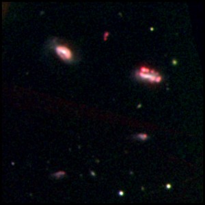 An optical image of one of the isolated galaxy groups observed with the Magellan Telescope in Chile. The red knots reveal emissions that signify recent and ongoing star formation. (Image by Kelsey E Johnson, Sandra E Liss, and Sabrina Stierwalt)