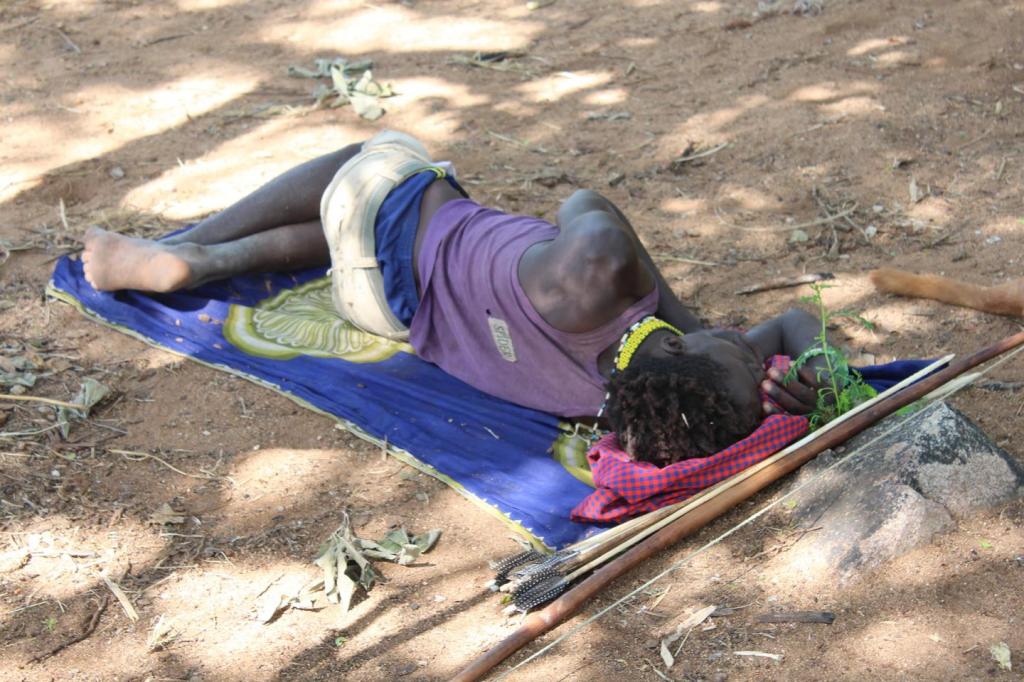 A Hadza man sleeps on the ground on an impala skin in northern Tanzania. (Image by David Samson)