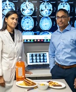 Drs. Sonya Anand and Russ de Souza stand behind a meal of ultra-processed foods and before a screen with the brain scans of people who eat lots of highly refined and processed foods regularly. Credit: Hamilton Health Sciences