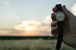 Photo: Person holding an analog watch as the sun rises; credit: Wil Stewart, Unsplash